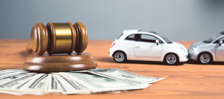 Two toy cars, parked alongside a judge's gavel atop a mound of money, illustrate the intriguing connection between legal decisions and financial implications.