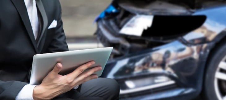 An insurance investigator reviewing a car accident claim report on a tablet
