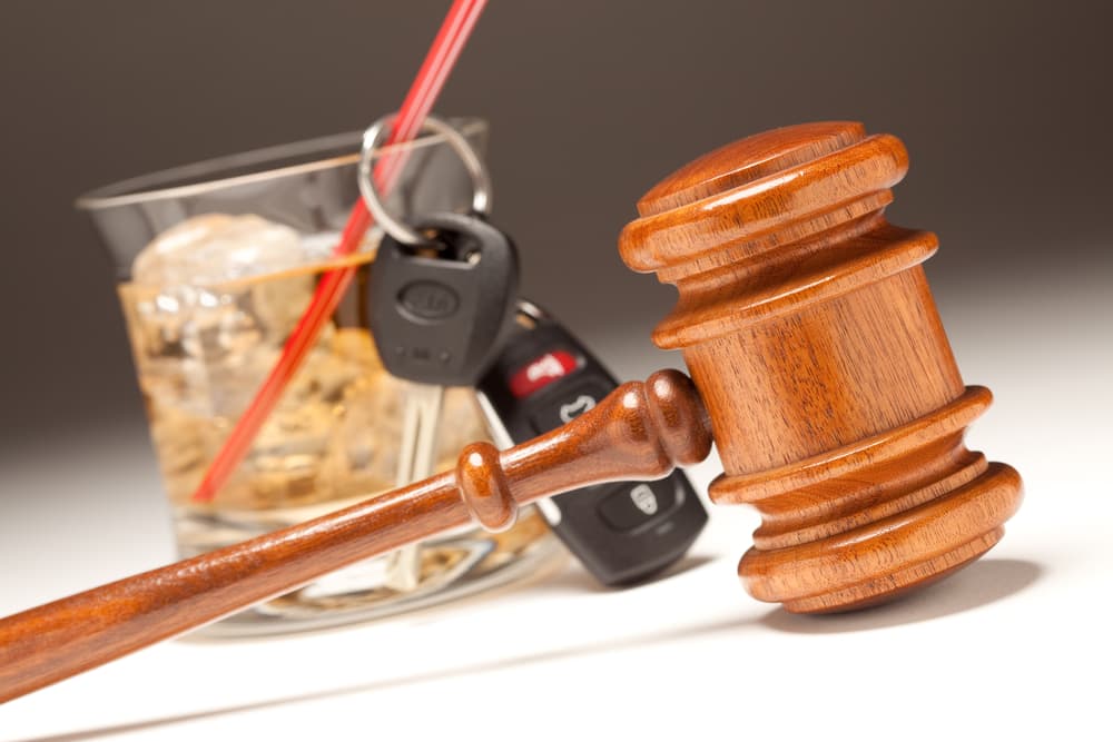 A legal gavel, a glass of wine, and car keys on a table