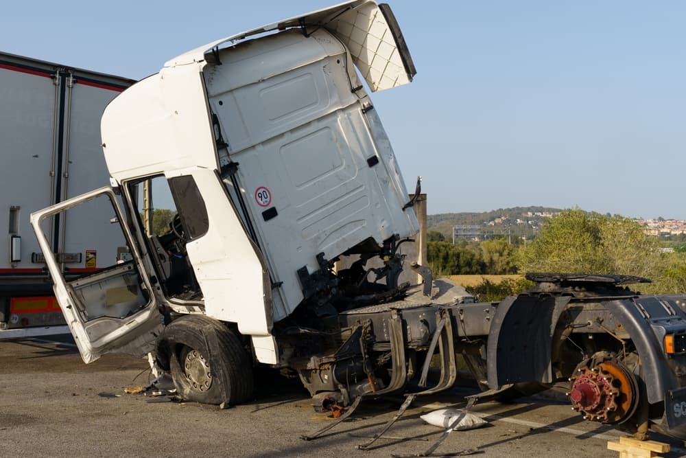 A truck damaged in an accident parked in a parking lot.