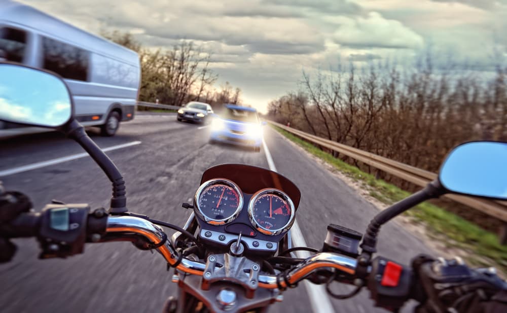 A speedy motorcycle in front of a car on the road