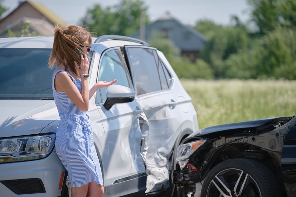 Sad female driver speaking on Cellphone on street side telling who hit in car accident.